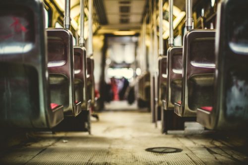 Interior view of an empty bus in Washington D.C., showcasing rows of vacant seats, metal support poles, and overhead handrails. Captured from a low angle, the image draws attention to the aisle leading toward the back, evoking a sense of stillness after a recent bustle.