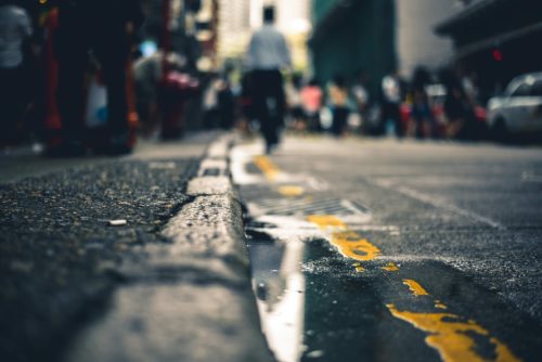 A wet urban street scene in Washington D.C. reveals a puddle reflecting blurred city lights. The focus is on the pavement and yellow lines, as people navigate around, creating a bustling atmosphere—a subtle reminder of premises liability claims in such vibrant settings.