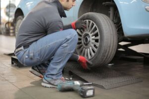 man changing tire on blue car